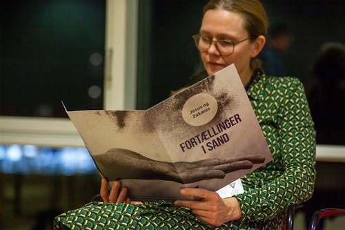 Kvinde laeser katalog 'fortaellinger i sand'